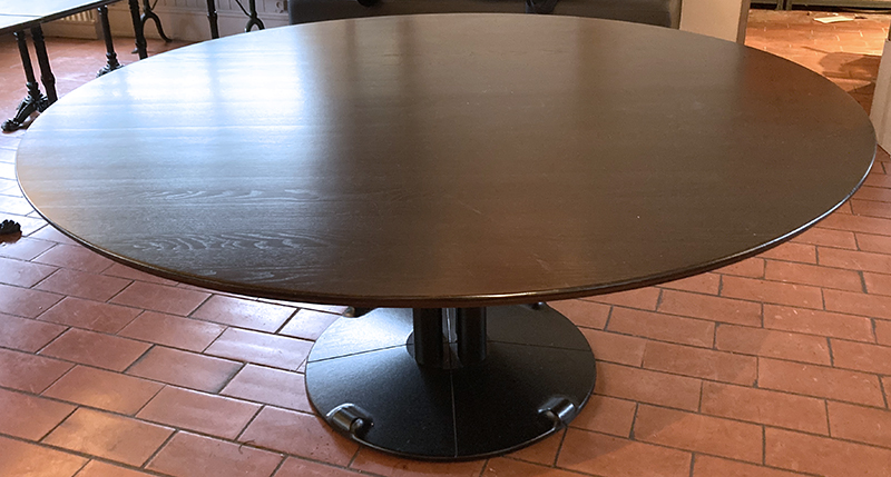 2 UNITES: TABLE CIRCULAIRE SUR ROULETTE A PLATEAU BISEAUTE EN BOIS VERNIS REPOSANT UN PIETEMENT COLONE CENTRALE EN FONTE LAQUEE NOIRE. 74 X 160 CM. 78100 SAINT-GERMAIN-EN-LAYE